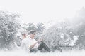 Young Asian college student couple sitting and relaxing together in the park, listening to music on smartphones Royalty Free Stock Photo