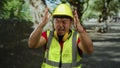 Young asian construction worker wearing protective gear in park setting expresses frustration Royalty Free Stock Photo