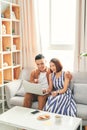 Young Asian couple buying online or paying bills by credit card with laptop at home Royalty Free Stock Photo