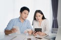 Young Asian couple is calculating their expenses with a home calculator. They feel stressed