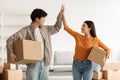 Young Asian couple with cardboard boxes high fiving each other in new home on moving day Royalty Free Stock Photo