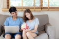 Young asian couple celebrate birthday together, asia man giving gift box present to woman for surprise at living room Royalty Free Stock Photo