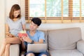Young asian couple celebrate birthday together, asia man giving gift box present to woman for surprise at living room Royalty Free Stock Photo
