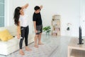 Young Asian couple doing High-intensity interval training together and looking TV at home, man and woman working out together