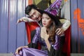 Young Asian couple dressed as witch and vampire. man is showing his fangs and sucking blood on woman`s neck at Halloween party Royalty Free Stock Photo