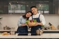 Young asian couple husband and wife having romantic and fun moment during coronavirus pandemic lock down cooking foods together at Royalty Free Stock Photo