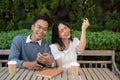 Young Asian couple listening to music together, having fun together in the green park Royalty Free Stock Photo