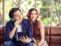 Young Asian couple listening to music wearing headphones on the couch at home Royalty Free Stock Photo