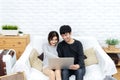 Young asian couple looking at laptop computer to search for travel plan, book hotel room, buy ticket or purchase travel insurance Royalty Free Stock Photo