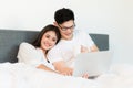 Young asian couple love man and woman watching movie in laptop on the bed in the morning. Happy moment concept Royalty Free Stock Photo