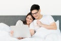 Young asian couple love man and woman watching movie in laptop on the bed in the morning. Happy moment concept Royalty Free Stock Photo