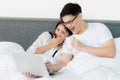 Young asian couple love man and woman watching movie in laptop on the bed in the morning. Happy moment concept Royalty Free Stock Photo