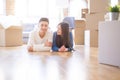 Young asian couple lying on the floor of new house arround cardboard boxes relaxing and smiling happy Royalty Free Stock Photo