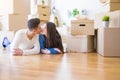 Young asian couple lying on the floor of new house arround cardboard boxes relaxing and smiling happy Royalty Free Stock Photo