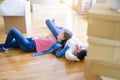 Young asian couple lying on the floor of new house arround cardboard boxes relaxing and smiling happy Royalty Free Stock Photo