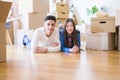 Young asian couple lying on the floor of new house arround cardboard boxes relaxing and smiling happy Royalty Free Stock Photo