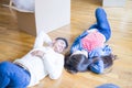 Young asian couple lying on the floor of new house arround cardboard boxes relaxing and smiling happy Royalty Free Stock Photo