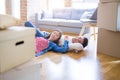 Young asian couple lying on the floor of new house arround cardboard boxes relaxing and smiling happy Royalty Free Stock Photo