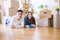 Young asian couple lying on the floor of new house arround cardboard boxes relaxing and smiling happy Royalty Free Stock Photo