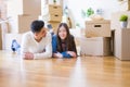 Young asian couple lying on the floor of new house arround cardboard boxes relaxing and smiling happy Royalty Free Stock Photo