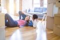 Young asian couple lying on the floor of new house arround cardboard boxes relaxing and smiling happy Royalty Free Stock Photo