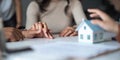 Young Asian couple making contract with house sale agency. man and his wife sitting signing the contract next to him Royalty Free Stock Photo