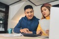 Young asian couple managing finances, reviewing their bank accounts using laptop computer and calculator at modern home. Royalty Free Stock Photo