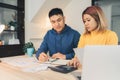 Young asian couple managing finances, reviewing their bank accounts using laptop computer and calculator at modern home. Royalty Free Stock Photo