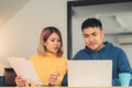 Young asian couple managing finances, reviewing their bank accounts using laptop computer and calculator at modern home. Woman and Royalty Free Stock Photo