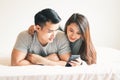 A young Asian couple plays a telephone in the bed in the bedroom.