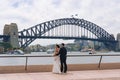 Young Asian couple posing against Sydney Harbour Bridge on background