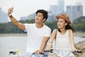 Young asian couple riding bike and taking a selfie
