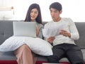 Young asian couple sit on a coach in bedroom discuss their works using notebook computer. Online work from home Royalty Free Stock Photo