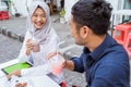 young Asian couple sits laughing and enjoying drinks together