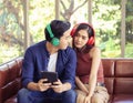 Young Asian couple sitting close together on couch ,looking happily to each other ,wearing headphones  listening to music from Royalty Free Stock Photo