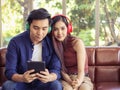 Young Asian couple sitting close together on couch ,wearing headphones  listening to music from tablet Royalty Free Stock Photo