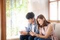 Young asian couple sitting on sofa with problem about relationship because addicts social network media together
