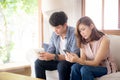 Young asian couple sitting on sofa with problem about relationship because addicts social network media together
