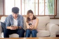 Young asian couple sitting on sofa with problem about relationship because addicts social network media together Royalty Free Stock Photo