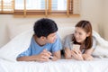 Young asian couple smile listen music with smart mobile phone on bed at bedroom with fun and enjoy Royalty Free Stock Photo