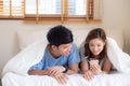 Young asian couple smile listen music with smart mobile phone on bed at bedroom with fun and enjoy Royalty Free Stock Photo