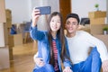 Young asian couple smiling taking a selfie photo with smartphone, moving to a new home together Royalty Free Stock Photo