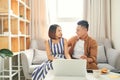 Young Asian couple smiling and using computer when sitting on sofa at home Royalty Free Stock Photo