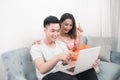 Young asian couple surfing on internet and shopping with laptop. Modern white apartment in background Royalty Free Stock Photo