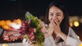 Young asian couple surprise moment with rose bouquet at romantic dinner in rooftop restaurant at city night with sweet moment Royalty Free Stock Photo