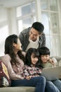 young asian couple and two children using laptop computer together at home Royalty Free Stock Photo