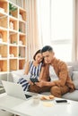 Young Asian couple using laptop and counting the utility bills and house maintenance documents Royalty Free Stock Photo