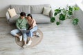 Young Asian couple using laptop, surfing internet or watching movie online, sitting on floor in living room, top view Royalty Free Stock Photo