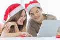 Young asian couple wearing red and white santa hat looking at each other smiling and lying down on clean white sheet bed surround Royalty Free Stock Photo