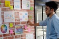 Young asian creative man reading and thinking about paper work ideas on office wall with concentration, working occupation Royalty Free Stock Photo